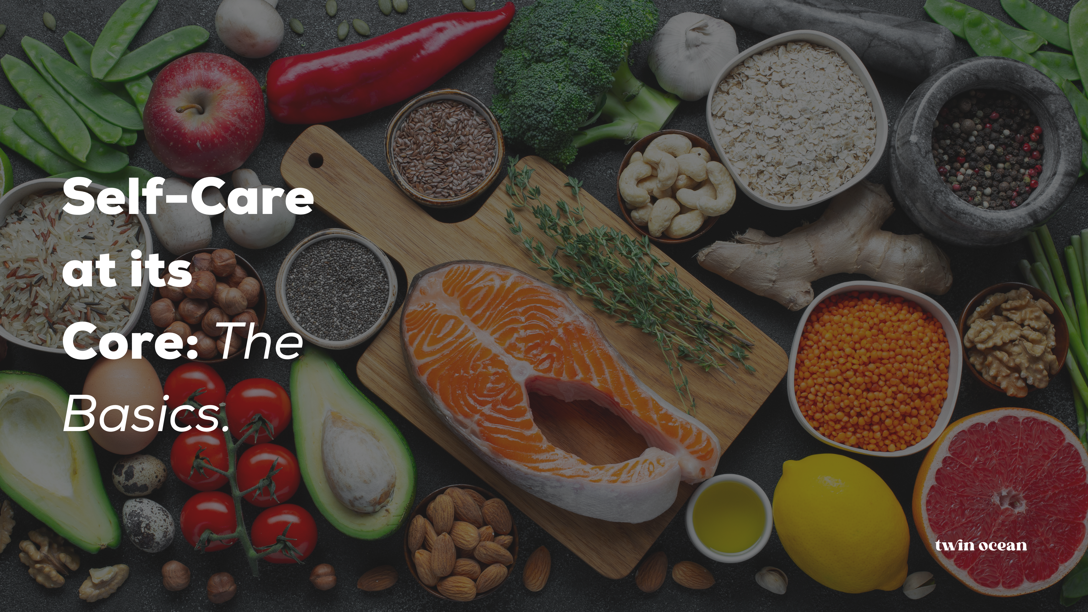 The image features a variety of healthy foods neatly arranged on a dark, textured surface. Included are fresh fruits like apples and avocados, vegetables like broccoli and red peppers, nuts, grains, seeds, and a fillet of salmon. Herbs, spices, and condiments are visible, presenting a colourful and balanced diet concept. The text "Self-Care at its Core: The Basics" is displayed at the top, with the Twin Ocean logo at the bottom right, emphasizing the theme of self-care.